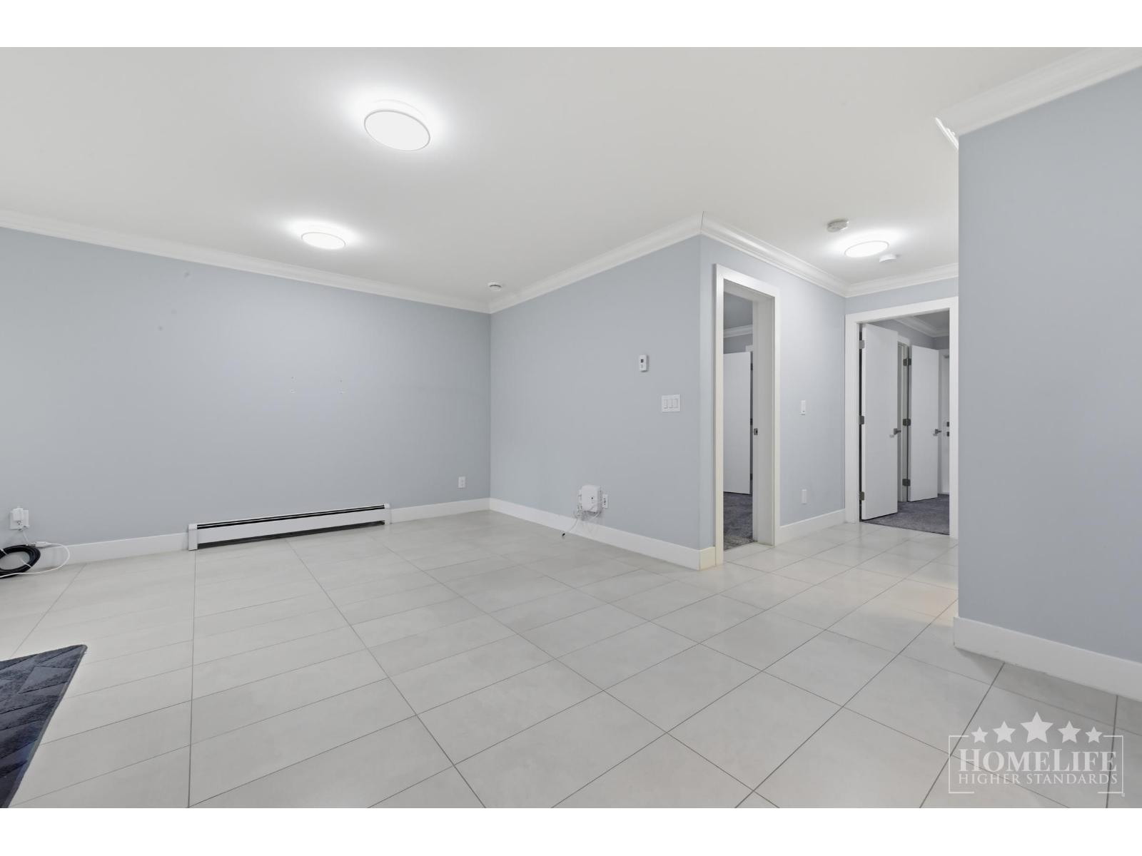 A spacious room with white tiled flooring and grey walls.