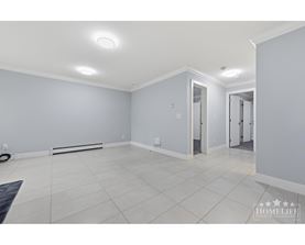 A spacious room with white tiled flooring and grey walls.