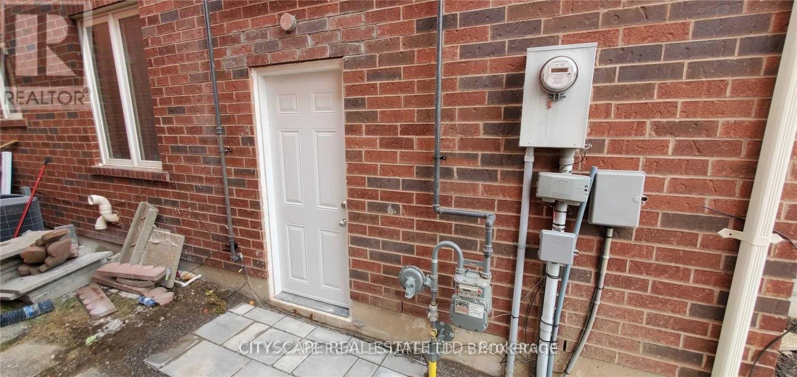 A white door is on the side of a brick building.