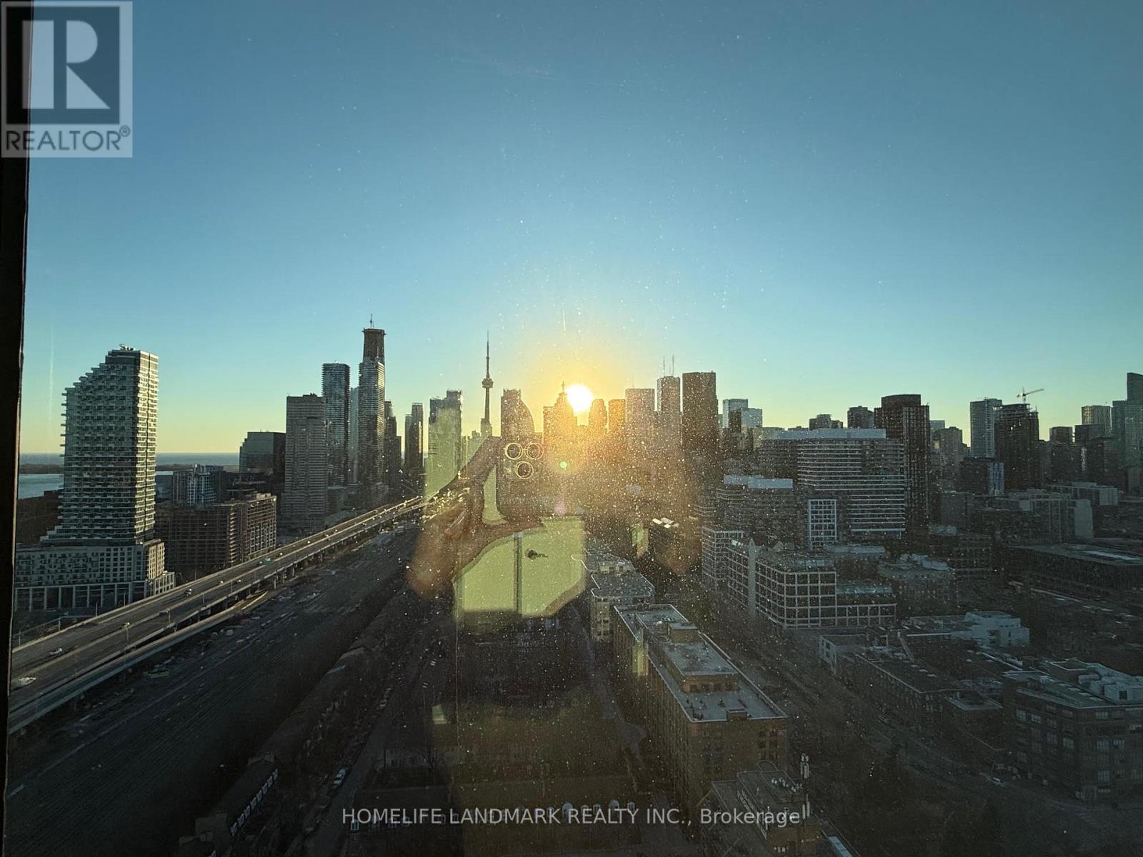 A cityscape with the sun setting behind the buildings.