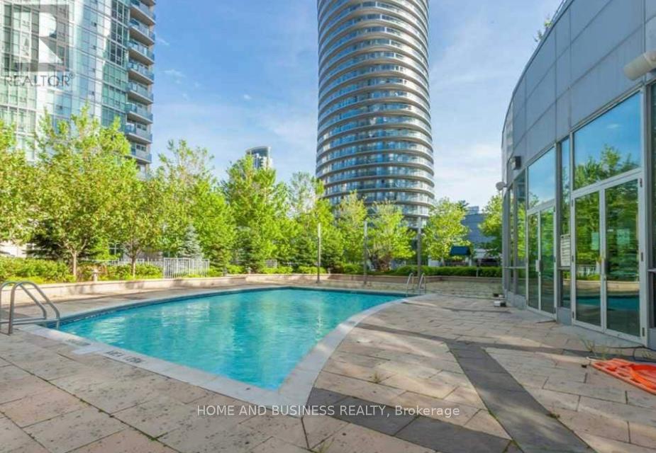 A swimming pool in a backyard with a glass building in the background.