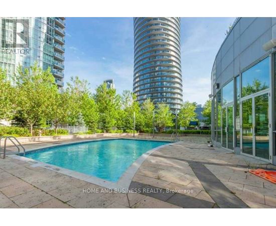 A swimming pool in a backyard with a glass building in the background.