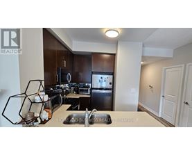 A well-lit kitchen with dark brown cabinets and a stainless steel refrigerator.
