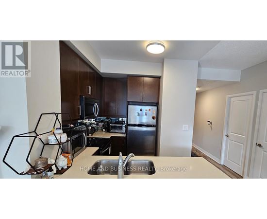 A well-lit kitchen with dark brown cabinets and a stainless steel refrigerator.