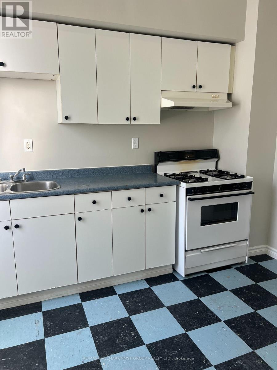 A kitchen with white cabinets and a black and white checkered floor.