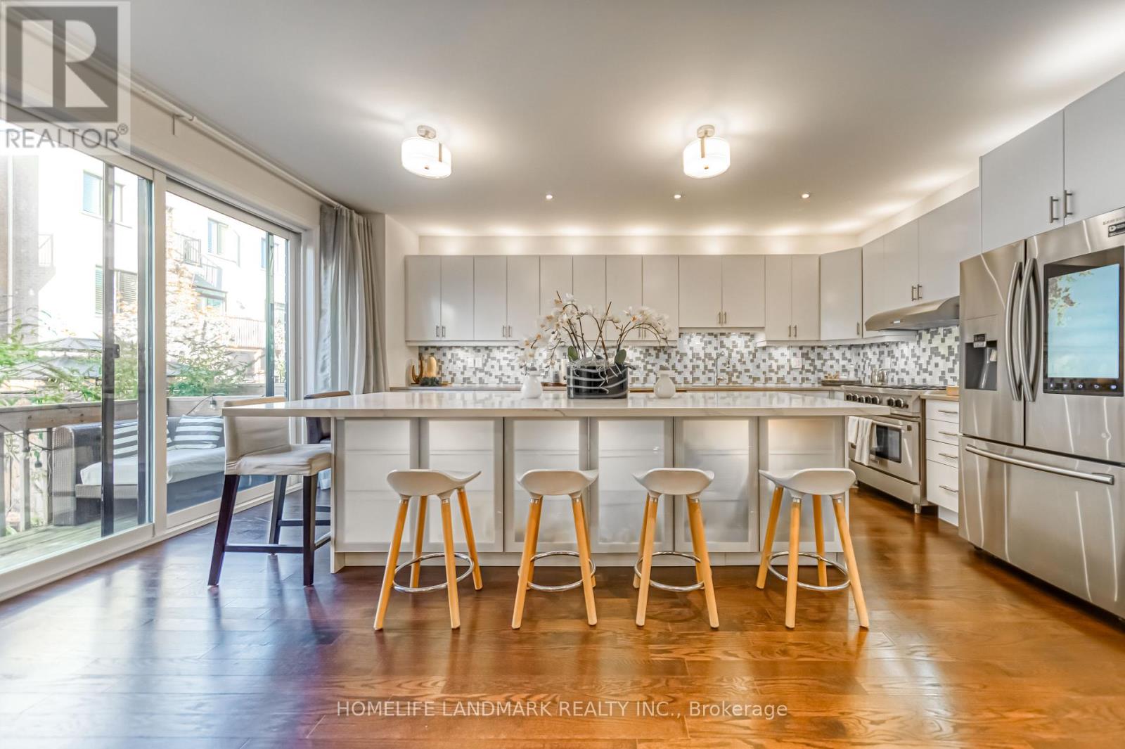 A kitchen with white cabinets and wooden stools.