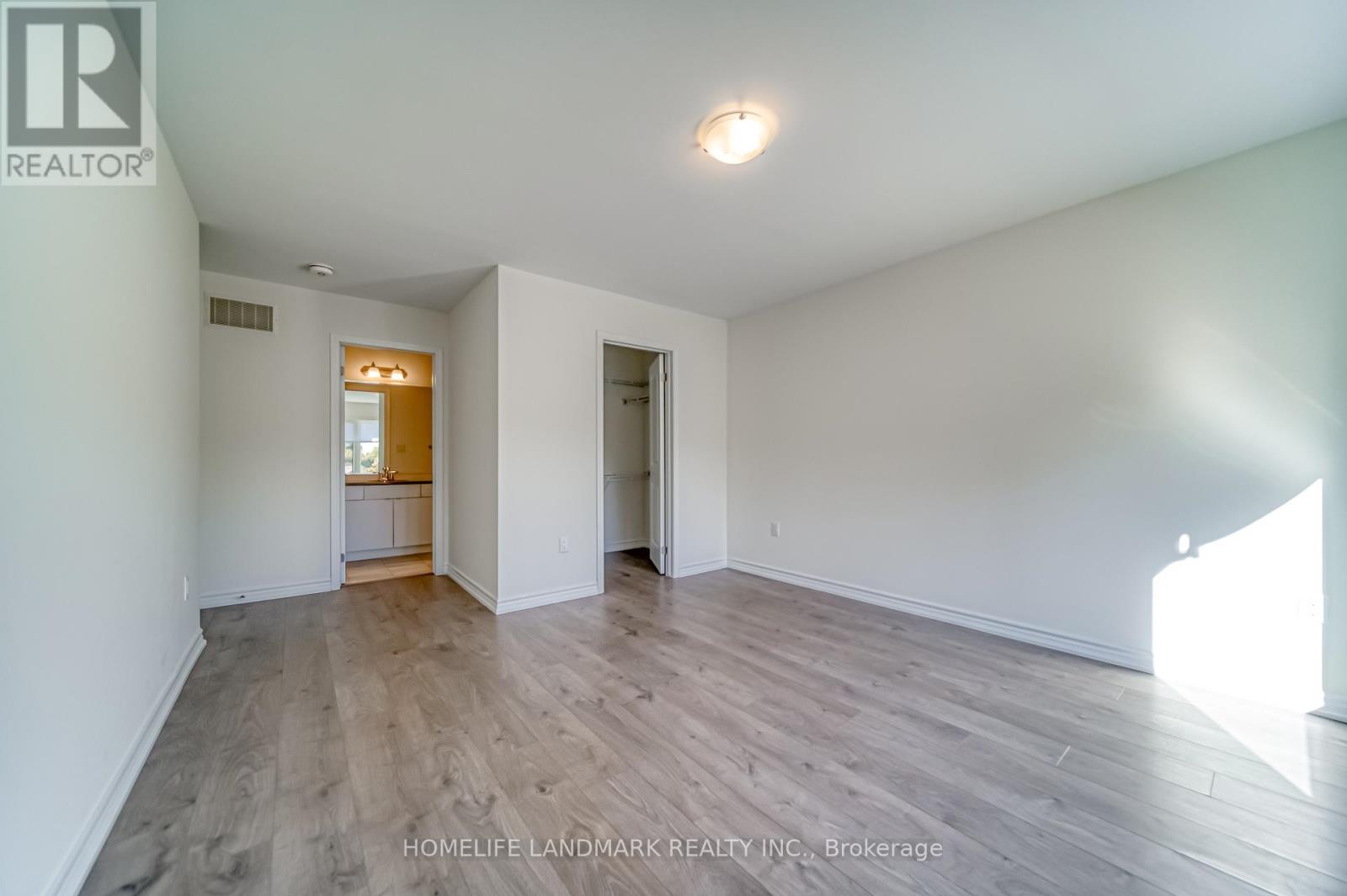 A spacious room with wooden flooring and white walls.