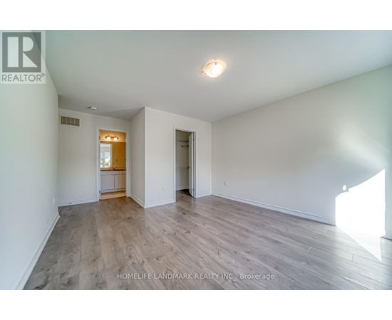 A spacious room with wooden flooring and white walls.