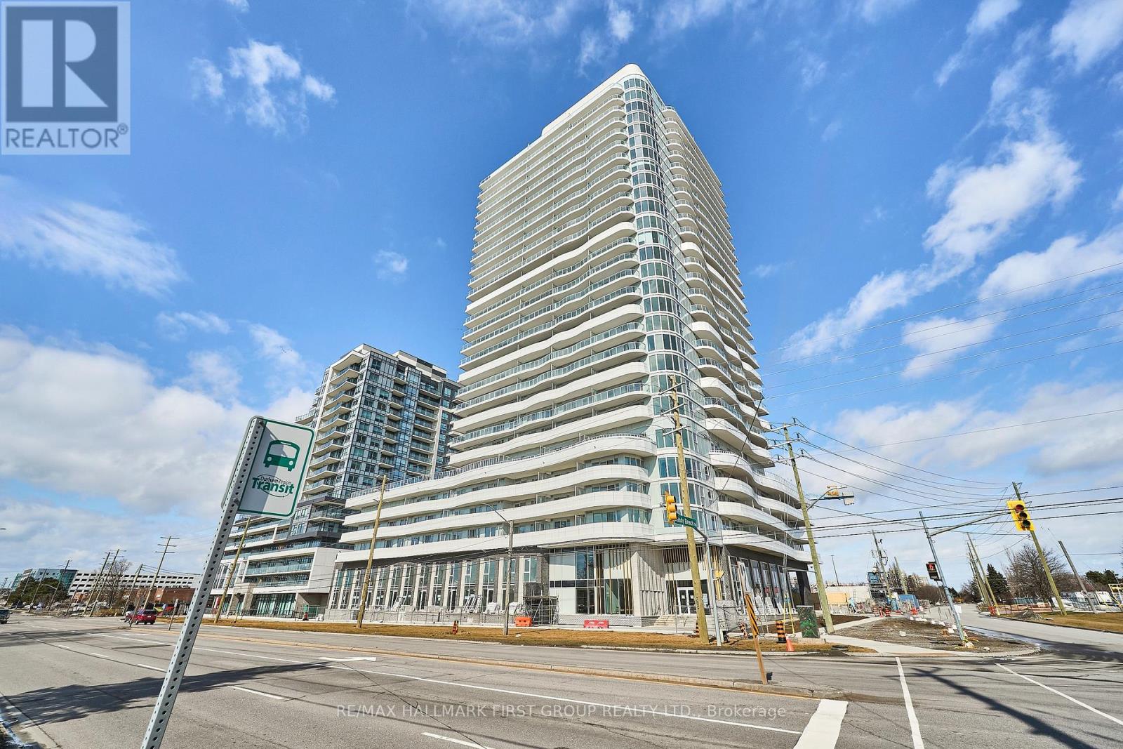A tall building with a glass facade stands in front of a smaller building with a sign that reads "REALTOR".