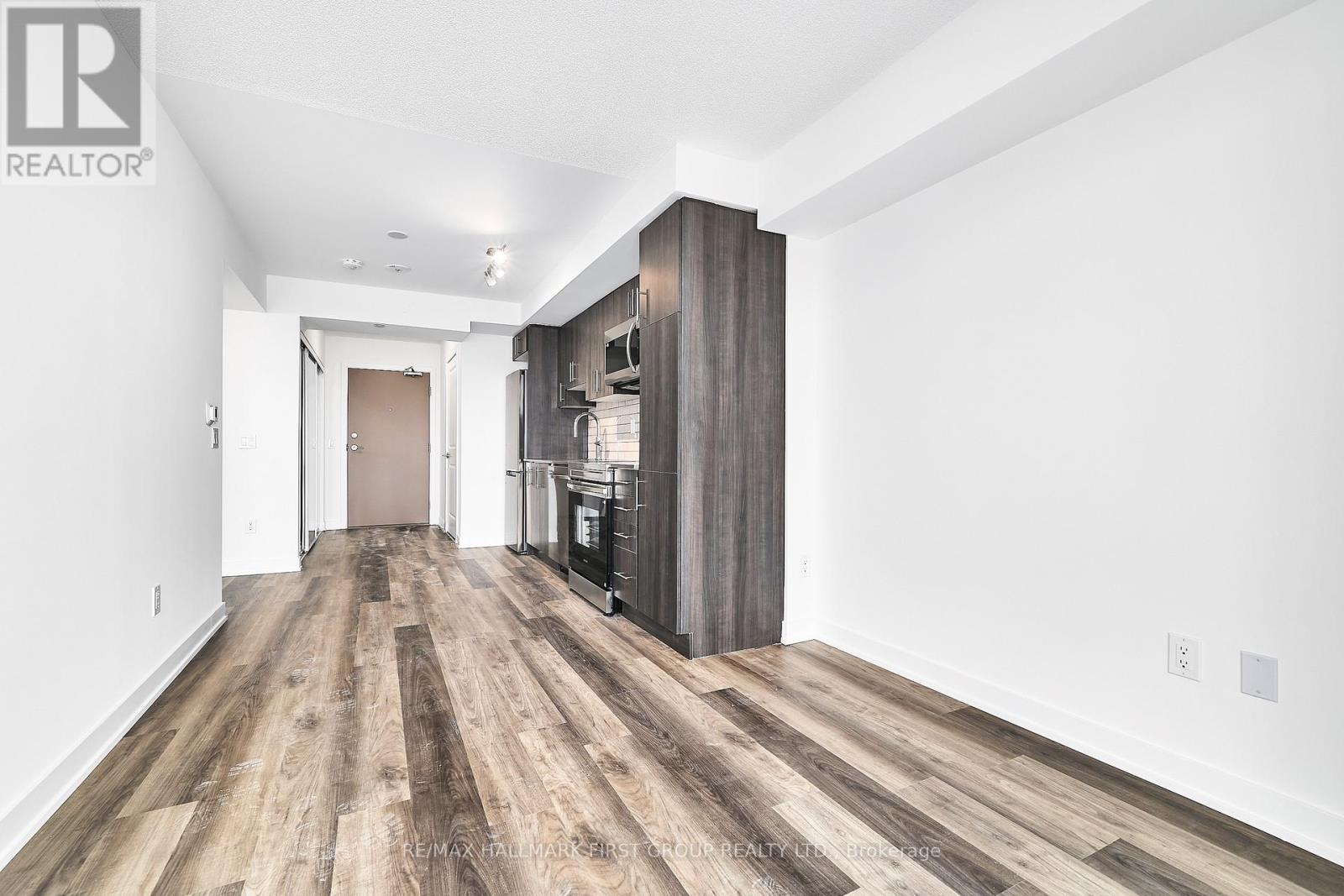 A spacious room with wooden flooring and a white wall.