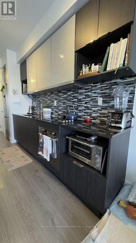 A kitchen with a black countertop and a microwave.