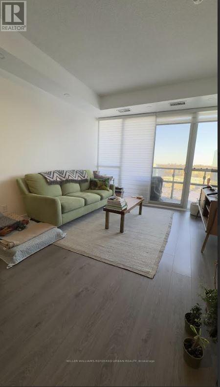 A living room with a couch, a rug, and a window overlooking the ocean.