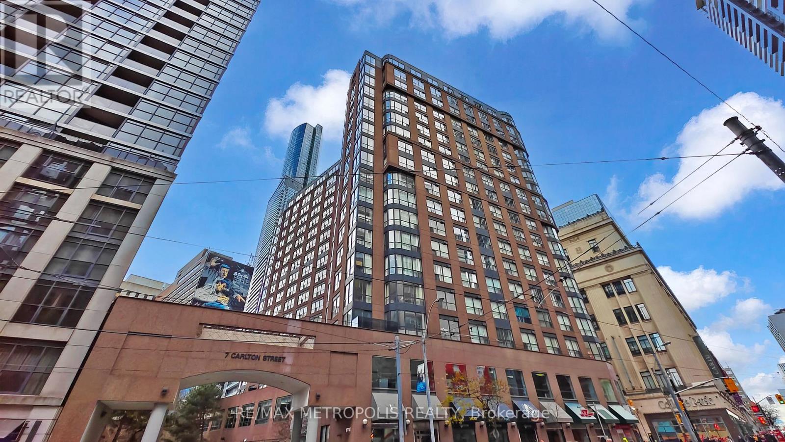 A tall building with the sign "Candlelight" is in the middle of a city street.