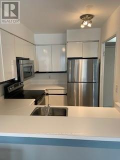 A kitchen with a stainless steel refrigerator and a sink.