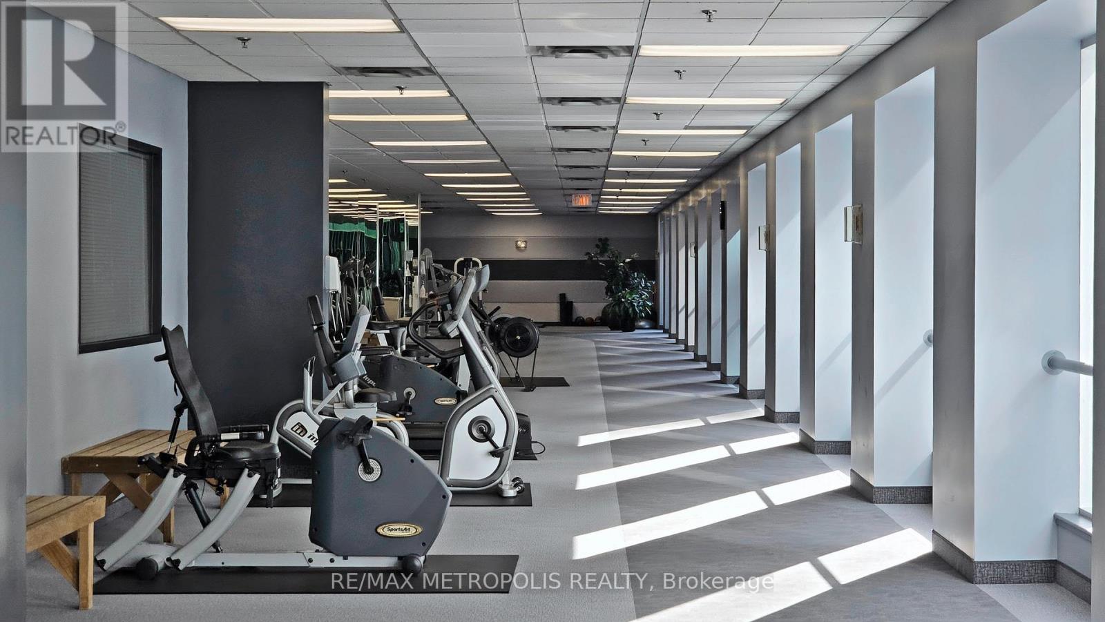 A gym with a row of treadmills and exercise bikes.