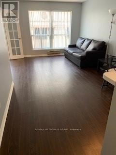 A living room with a black couch and wooden floors.