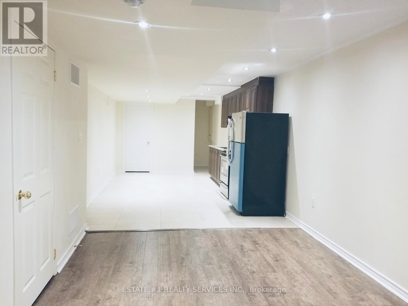 A spacious room with a white door, a black cabinet, and a wooden floor.