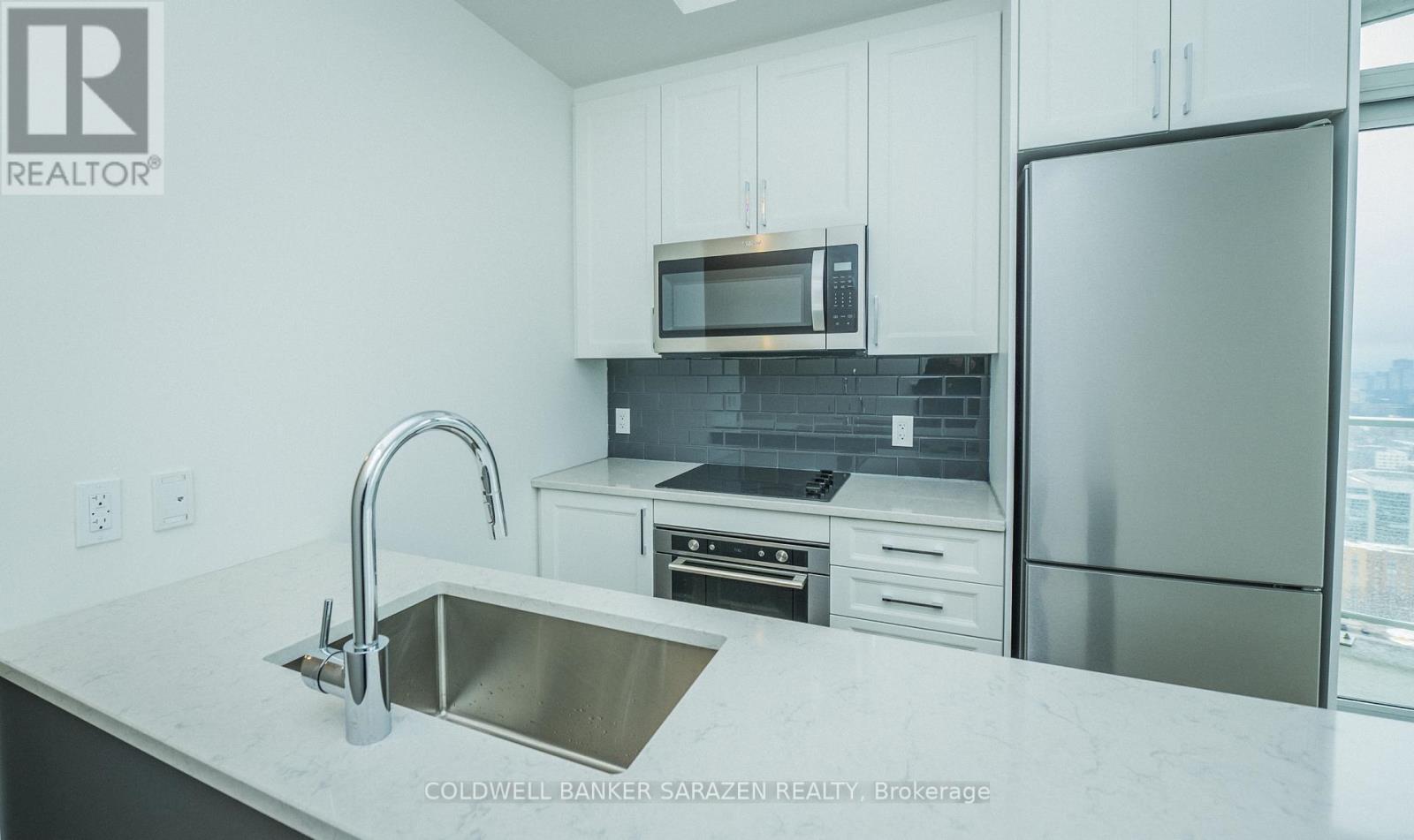 A modern kitchen with a stainless steel sink and refrigerator.