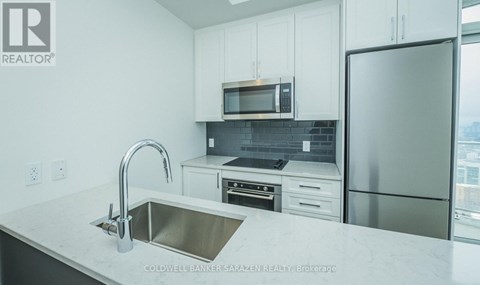 A modern kitchen with a stainless steel sink and refrigerator.
