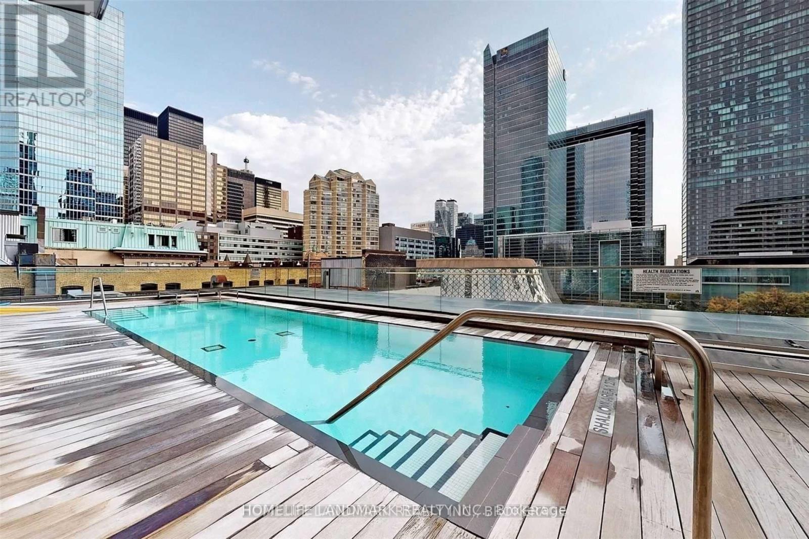 A pool on a wooden deck with a cityscape in the background.