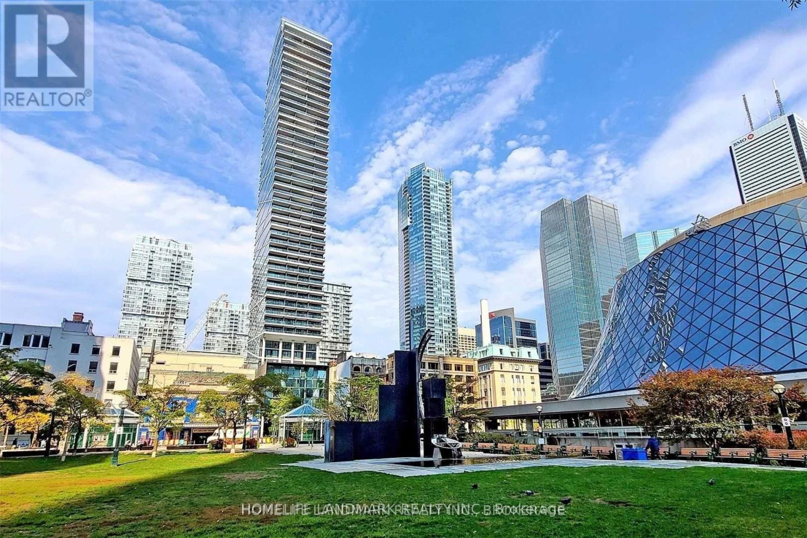 A cityscape with a tall building in the background and a monument in the foreground.