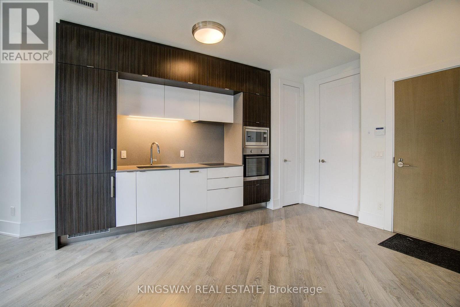 A modern kitchen with white cabinets and a wooden floor.