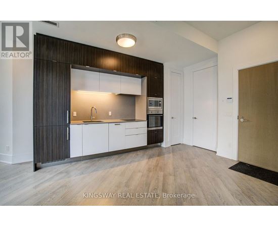 A modern kitchen with white cabinets and a wooden floor.