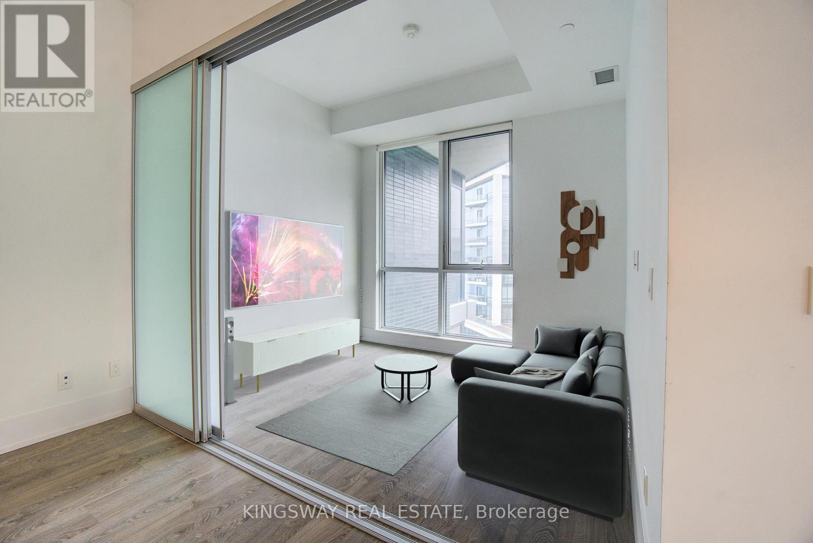 A living room with a couch, a coffee table, and a sliding glass door leading to a balcony.