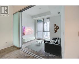 A living room with a couch, a coffee table, and a sliding glass door leading to a balcony.