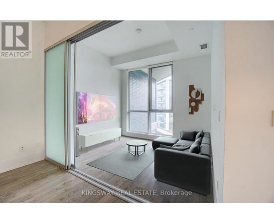 A living room with a couch, a coffee table, and a sliding glass door leading to a balcony.