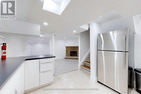 A modern kitchen with white cabinets and a stainless steel refrigerator.