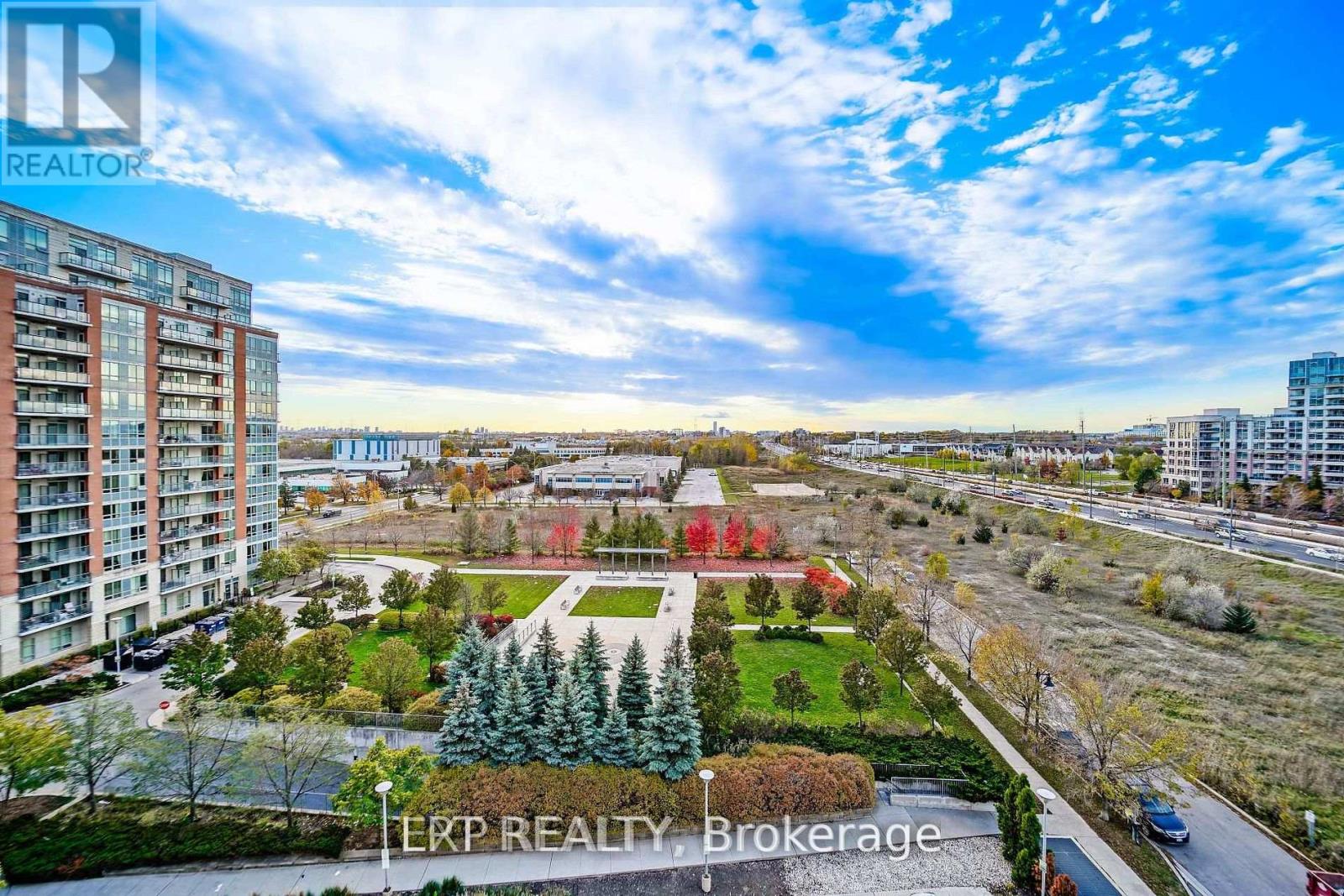 A real estate brokerage logo is displayed on a sunny day over a residential area.