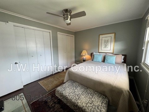 A bedroom with a bed, a ceiling fan, and a picture frame on the wall.