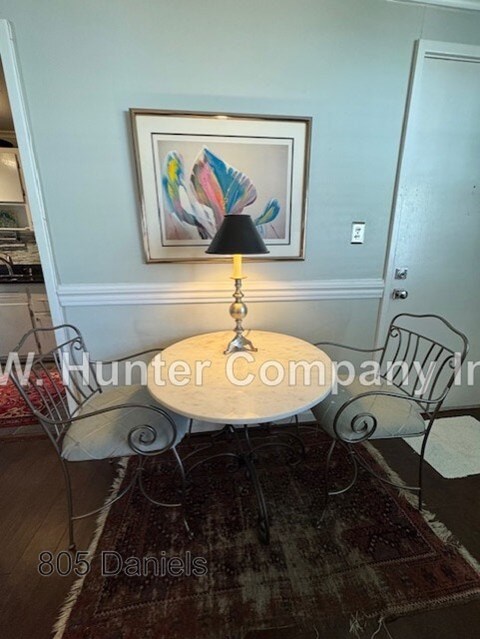 A dining room with a table, chairs and a painting on the wall.