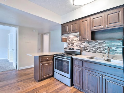 A kitchen with wooden cabinets and a stone backsplash.