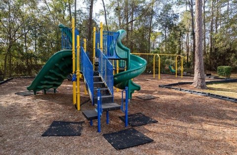 Playground with a green slide and a blue and yellow structure.