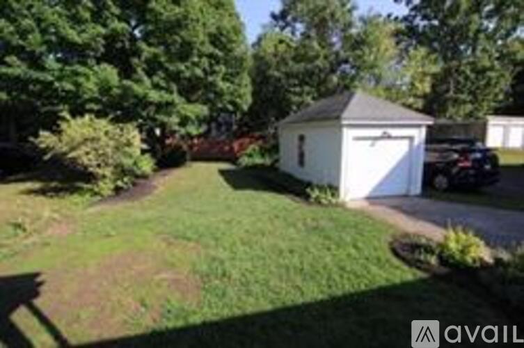 A small white shed sits in a grassy yard.