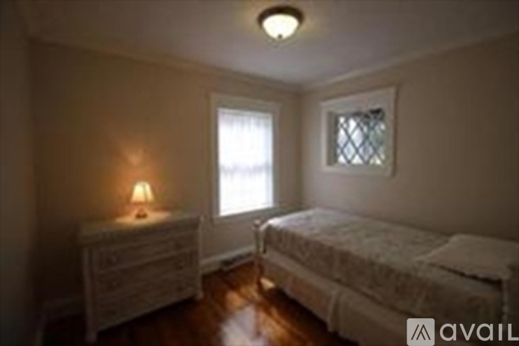 A bedroom with a bed, nightstand and window.