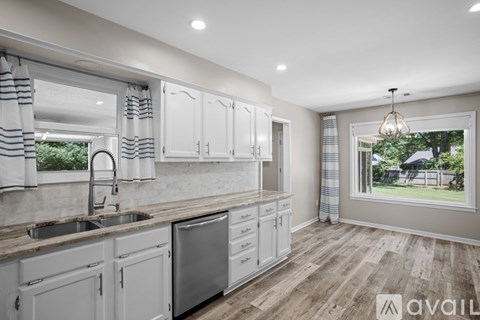 A kitchen with white cabinets and a wooden floor.