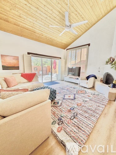 A living room with a rug on the floor and a ceiling fan.