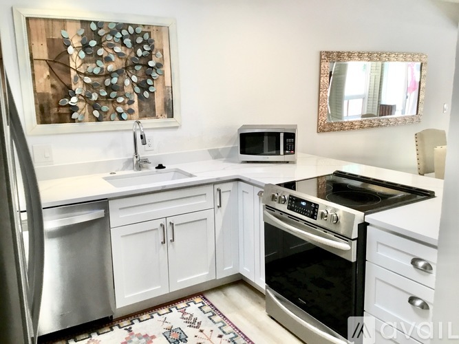 A kitchen with white cabinets and a stainless steel refrigerator.