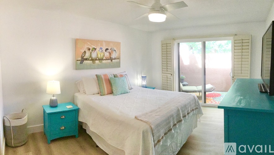 A bedroom with a bed, nightstand, and a painting on the wall.