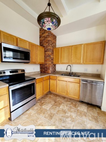 A kitchen with wooden cabinets and a brick chimney.