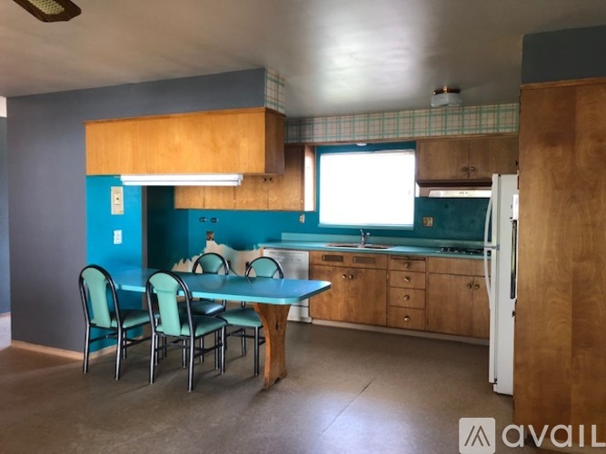 A kitchen with a table and chairs in front of a blue wall.