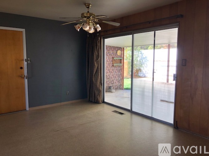 A room with a ceiling fan and sliding glass doors.