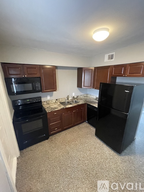 A kitchen with black appliances and brown cabinets.