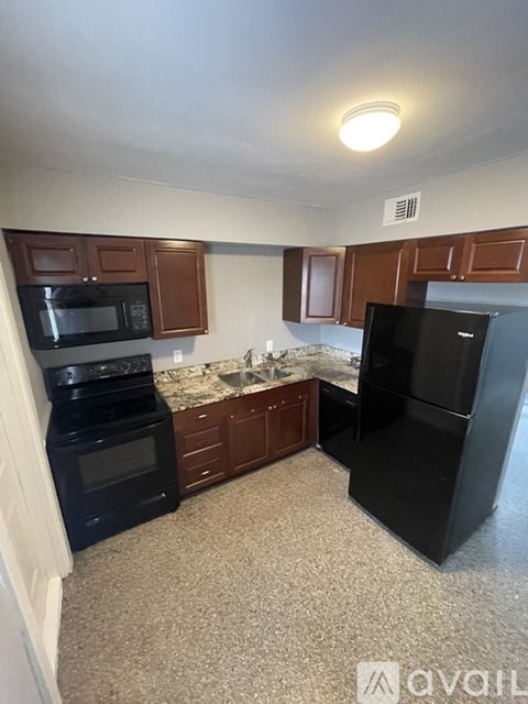 A kitchen with black appliances and brown cabinets.