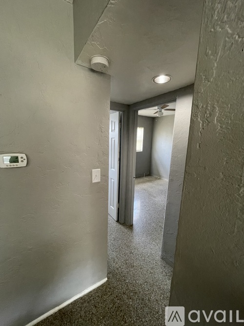 A hallway with a door on the right and a wall-mounted thermostat on the left.