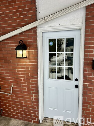 A white door with a glass window is on a brick wall.