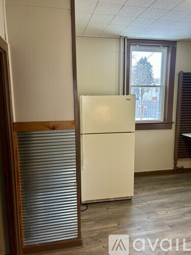 A white refrigerator in a room with a window.